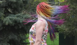 A woman with vibrant, fantasy hair dye dancing joyfully.