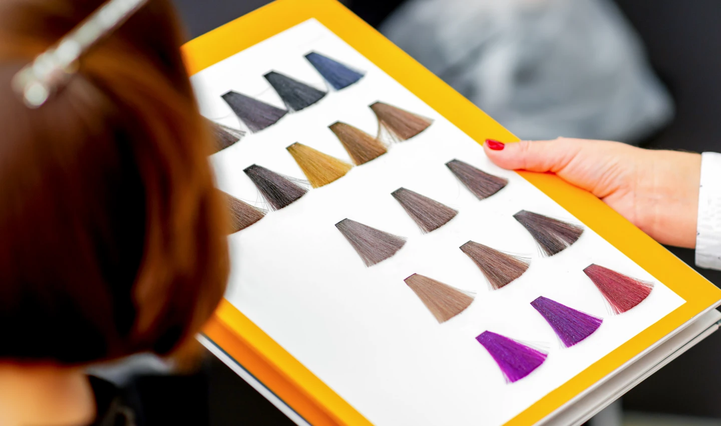 Young Caucasian woman choosing a color from the non-toxic hair dye chart in a beauty salon