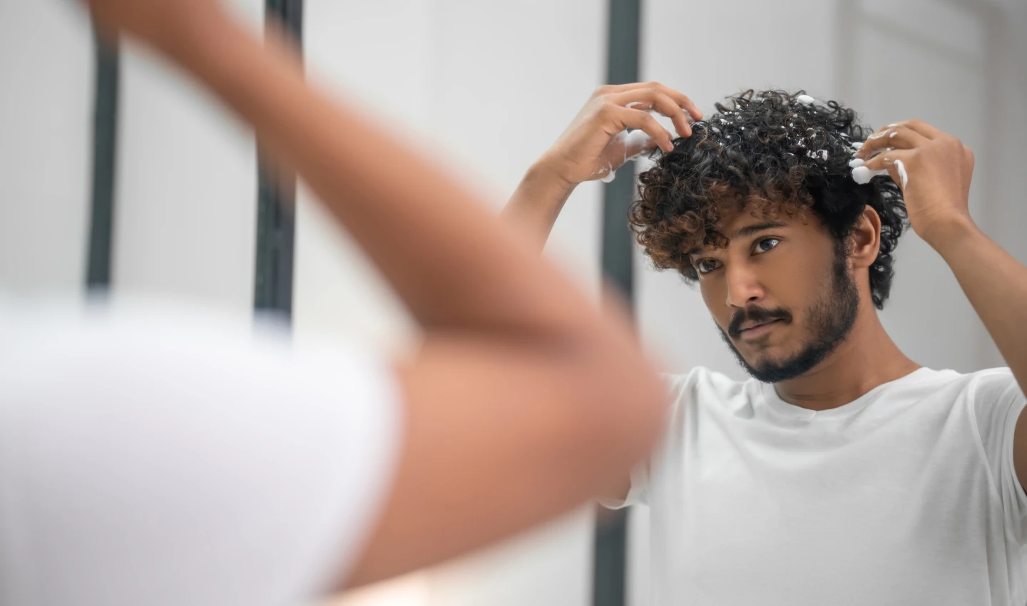 Curly Hair Shampoo Men - Image of curly-haired handsome young Indian guy styling his hair