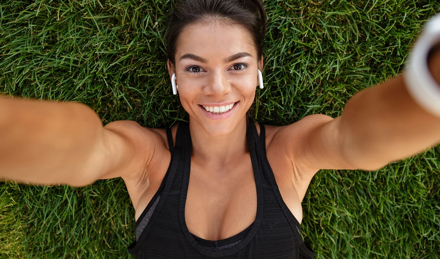 An athletic woman lying on the grass and smiling, symbolizing the positive outcome of lifestyle changes made in preparation for facelift surgery.An athletic woman lying on the grass and smiling, symbolizing the positive outcome of lifestyle changes made in preparation for facelift surgery.