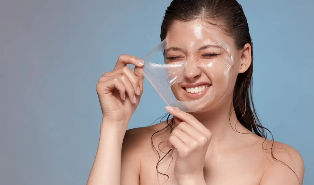 Image of a happy woman removing her facial mask with hardness, revealing fine line of exfoliation