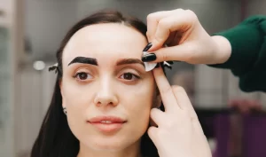 Eyebrow Pencil Magic: Closeup of a young woman undergoing an eyebrow correction procedure in a beauty salon.