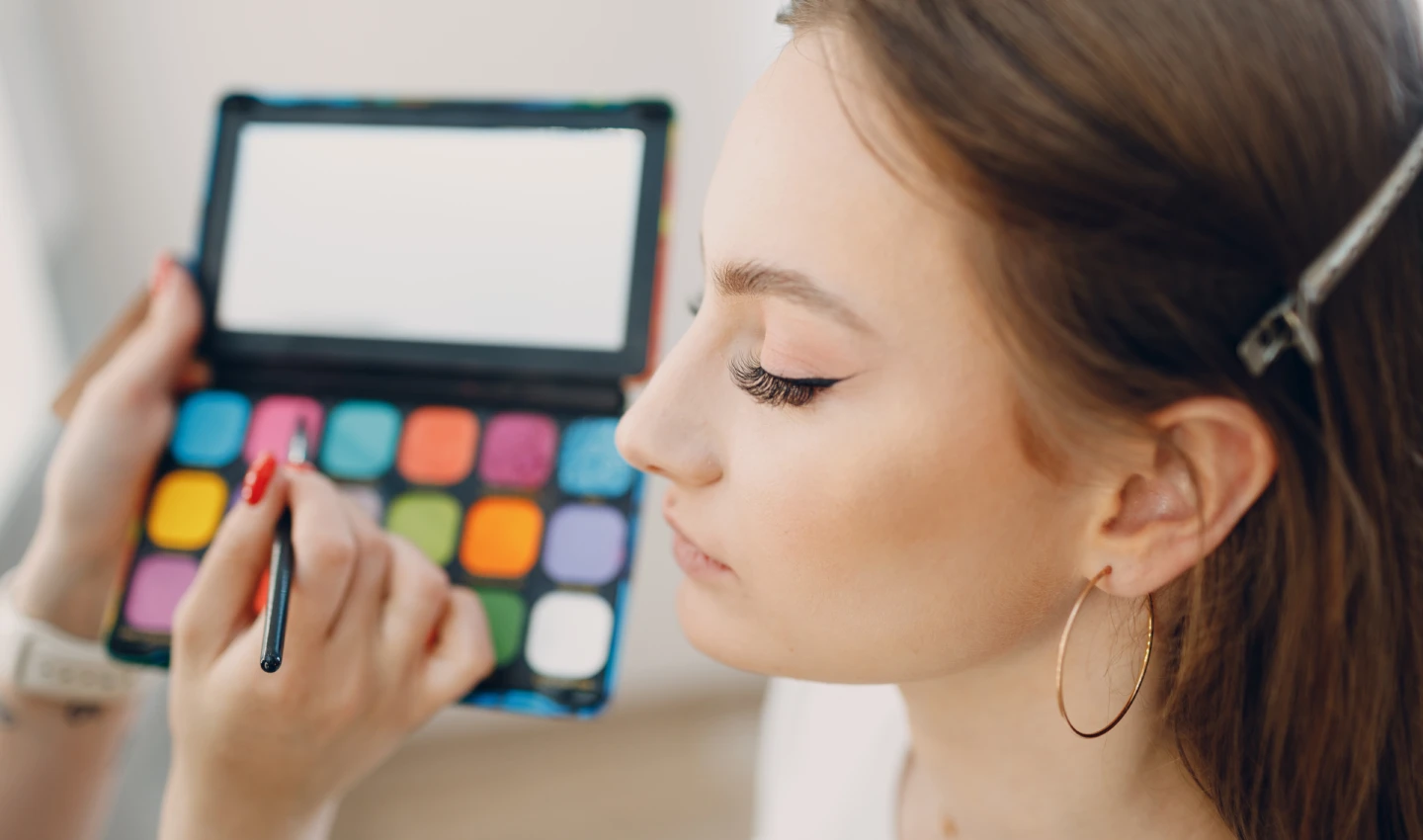 Perfect Eyeshadow Palette - Image of a beautiful young woman applying makeup with a beauty visage brush