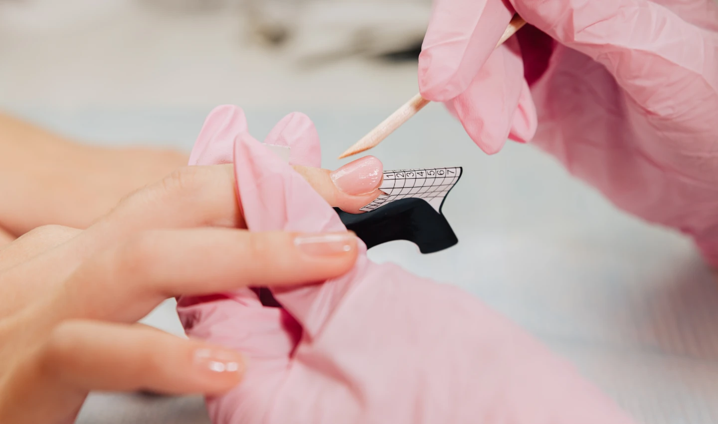 Image of the manicure process where the master forms an artificial nail from a special gel using a bamboo stick for unchippable gel manicures.