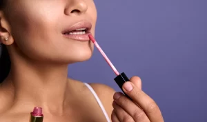 Close-Up of Attractive Young Woman Applying Lip Gloss for Glam Makeup