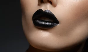 A woman applying black lipstick