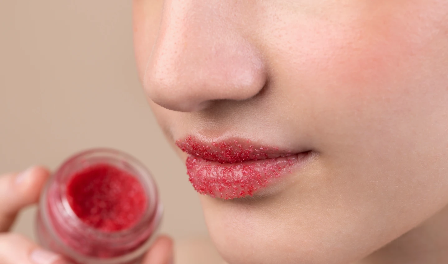 Close-up image of a girl holding a lip scrub container for lip stain feathering