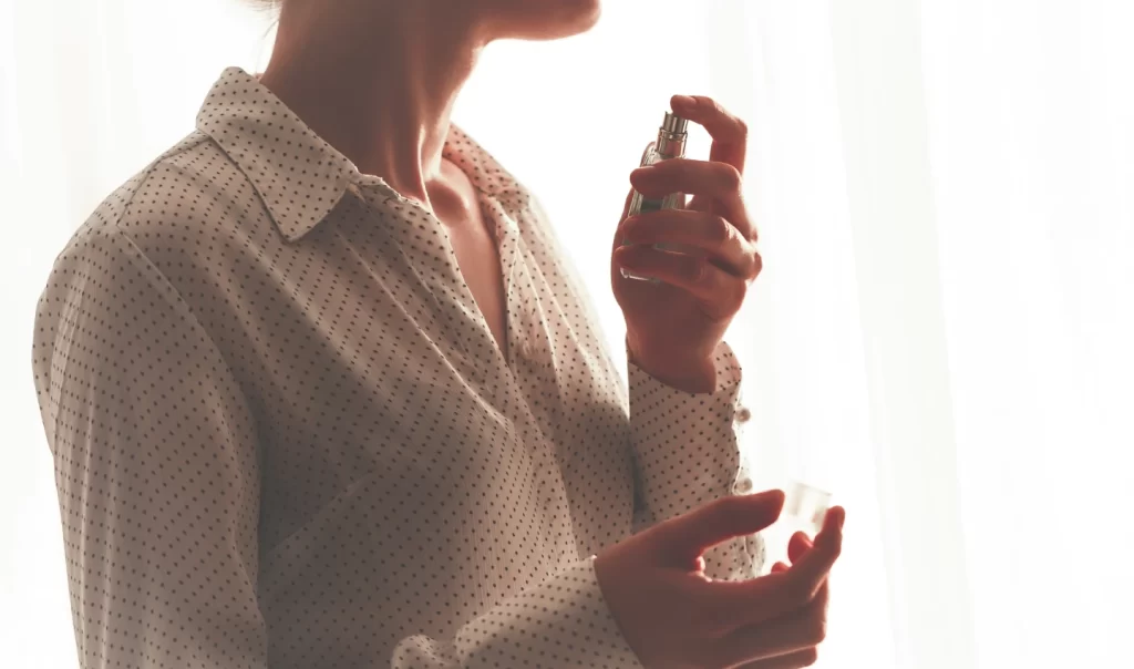 A woman elegantly spritzing perfume on her wrist, embodying the science and artistry that goes into creating and experiencing the perfect scent