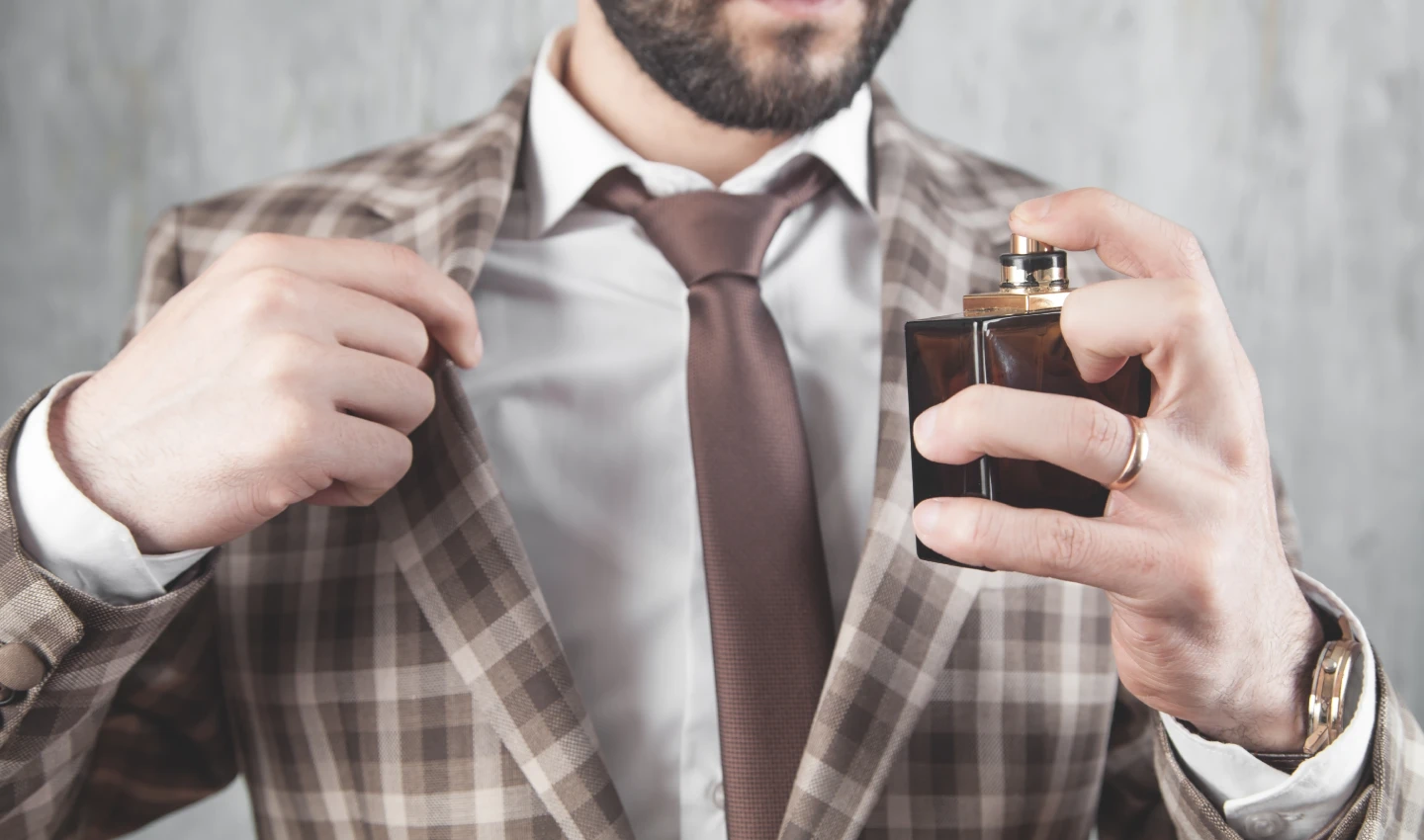 A man spraying perfume on himself as a representation of consumer engagement in perfume production impacts.