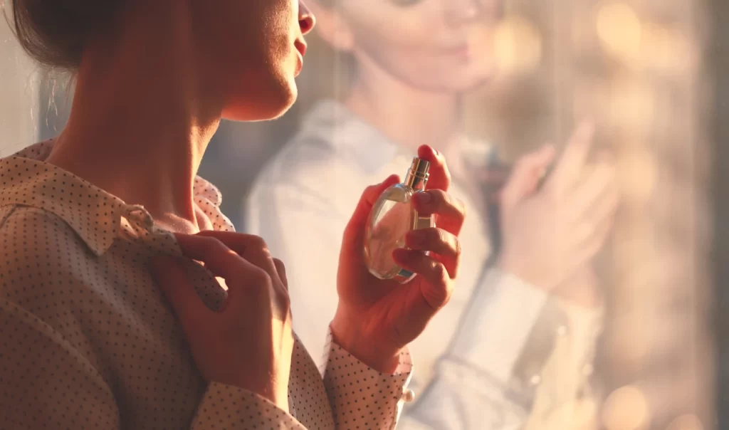 A woman applying perfume, demonstrating a step towards achieving long-lasting fragrance bliss.