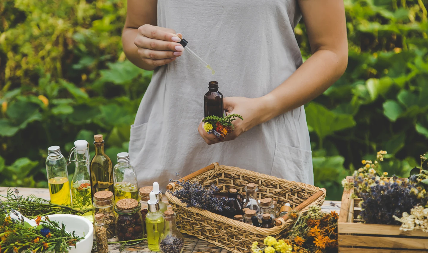 A woman crafting perfume in a natural setting, highlighting the role of essential oils in perfumes
