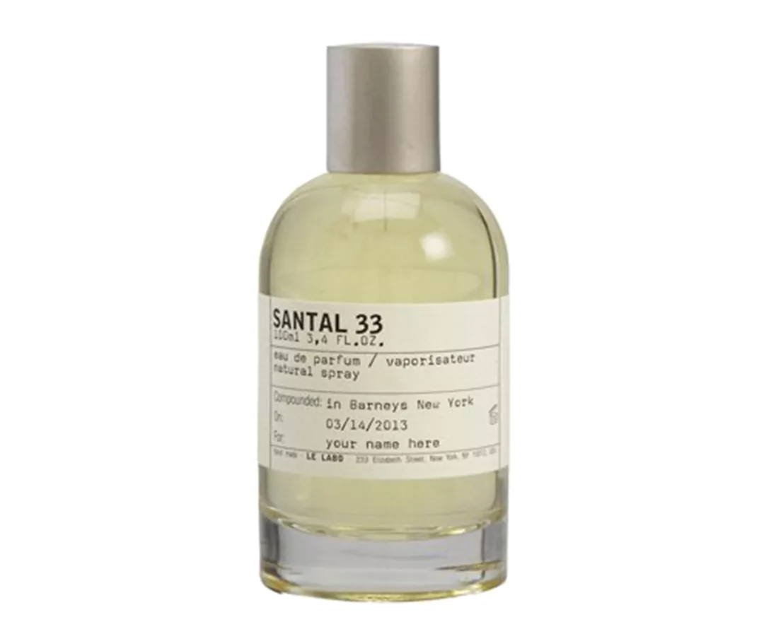 Santal 33 Le Labo perfume bottle on a dark wooden surface, reflecting its warm, woody, and oriental scent profile