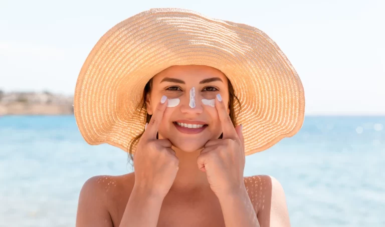 A stunning, fit woman with healthy skin applying sunscreen to prevent aging.