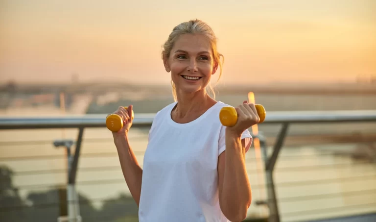 A woman exercising on a beach, with the ocean in the background.