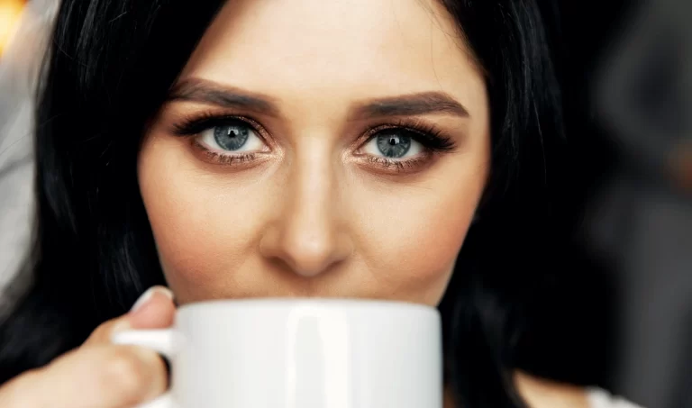 Young woman enjoying a cup of coffee, highlighting the benefits of caffeine for under-eye puffiness
