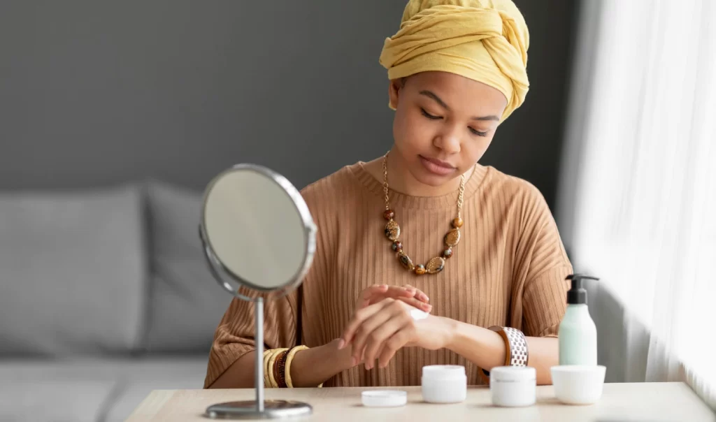 A woman delicately applies various creams to her face, striving for an even skin tone