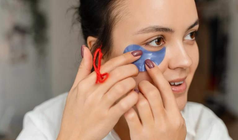 A young woman with captivating eyes applies under-eye masks to address under-eye puffiness