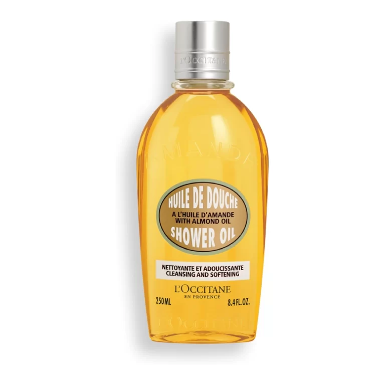 A bottle of L'Occitane Almond Shower Oil with almond flowers and almonds around it.